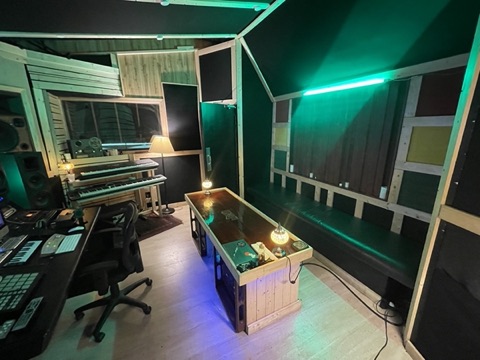Live room with built-in acoustic-paneled bench seating under green mood lighting